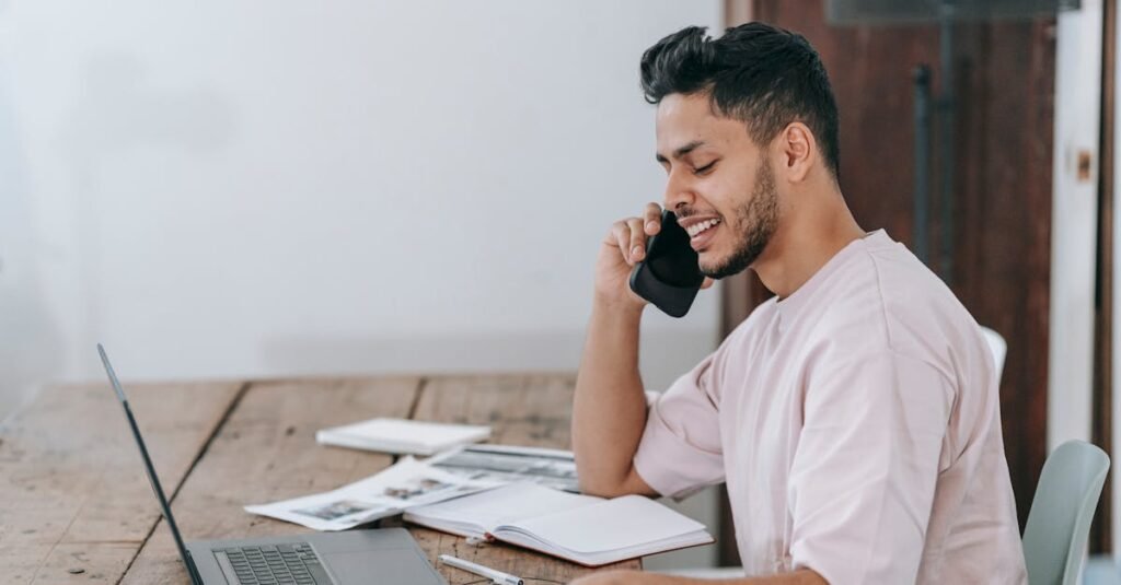 Happy businessman speaking on phone at workplace